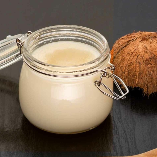 jar of homemade cream of coconut on table next to coconut