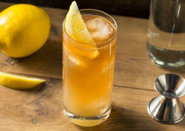 a glass of Long Island Iced Tea with lemon wedge on wooden table