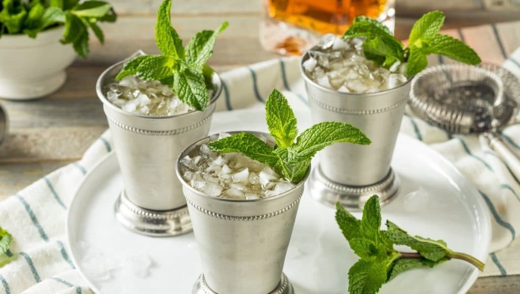 Bourbon-based Mint Julep cocktails on silver tray