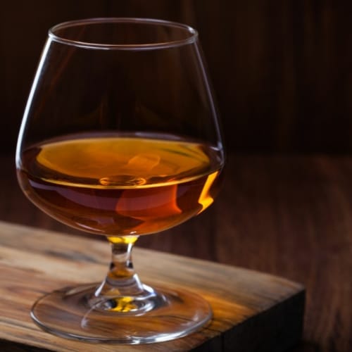 Bourbon served in Snifter glass on wooden table
