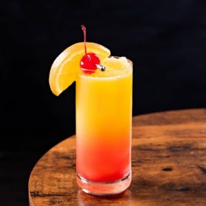 Tequila Sunrise cocktail with orange wedge and cherry