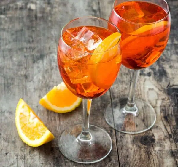 Two Aperol Spritz cocktails on wooden surface