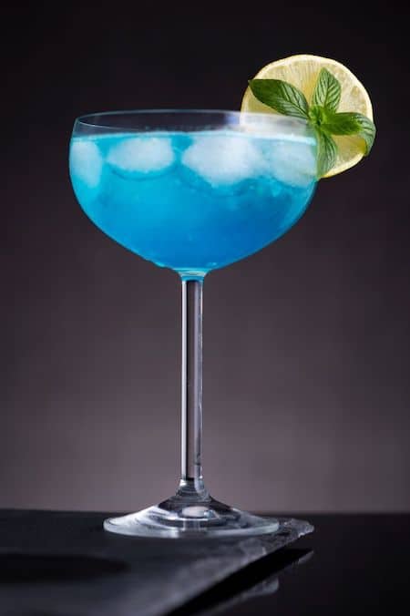 Blue Lagoon Cocktail on black plate garnished with lemon