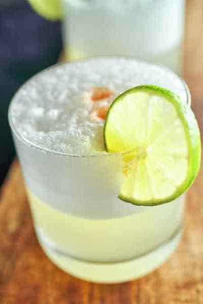Tequila Sour drink with lime wheel and aromatic bitters