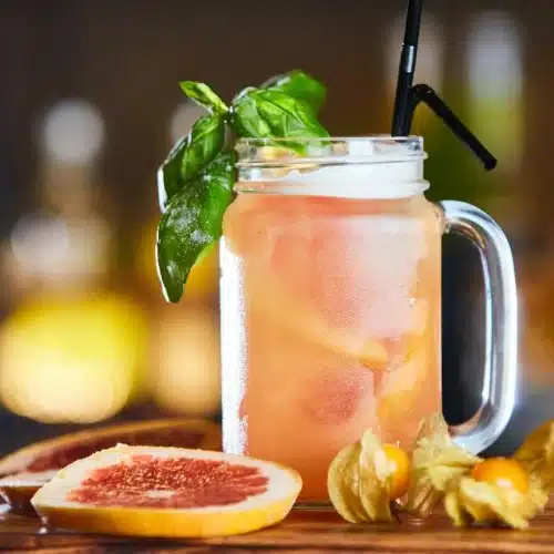 Easy Lynchburg Lemonade next to fresh grapefruit slices with blurry background