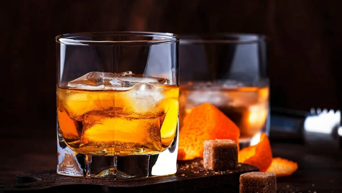 Bitters in Old Fashioned cocktail served in glass with sugar cube and orange peel
