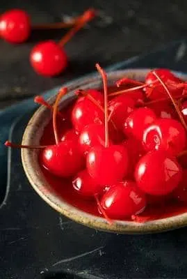 artificial and bright red maraschino cherries on bowl