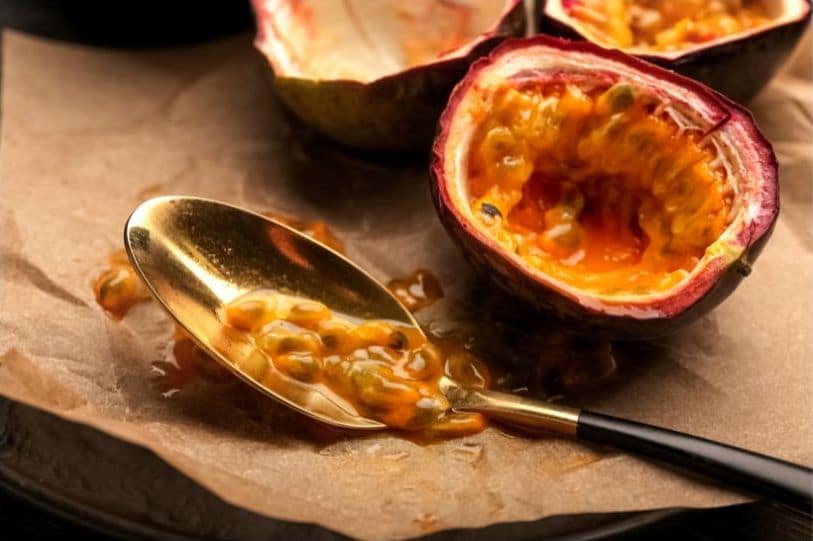 Passion fruit pulp with spoon on wooden board