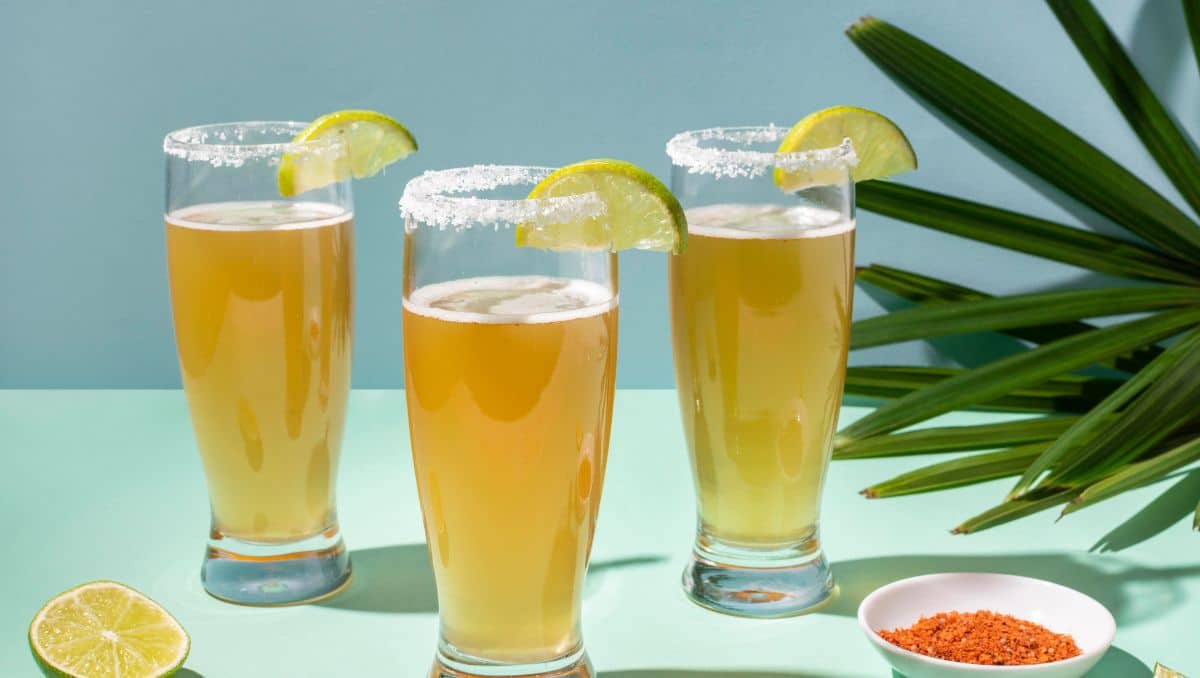 Three Chelada cocktails with lime and Tajin