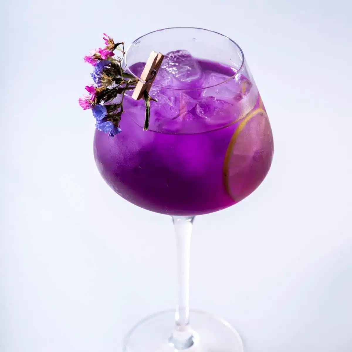 Empress Gin cocktail with flower garnish on white background