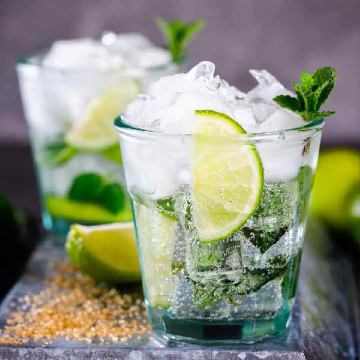 Non-alcoholic Mojito Cocktails on table with limes and sugar on the side