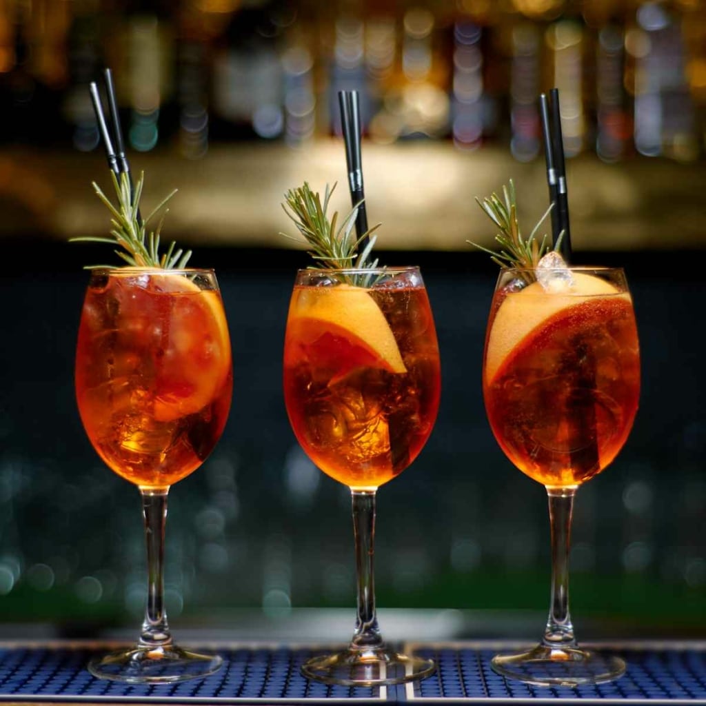 Three Amaro Spritz cocktails garnished with orange and rosemary