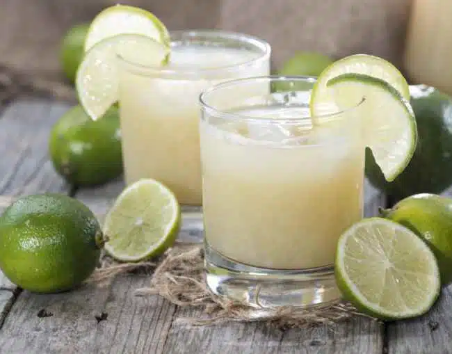 Lime juice mixed with gin and fresh limes on the side